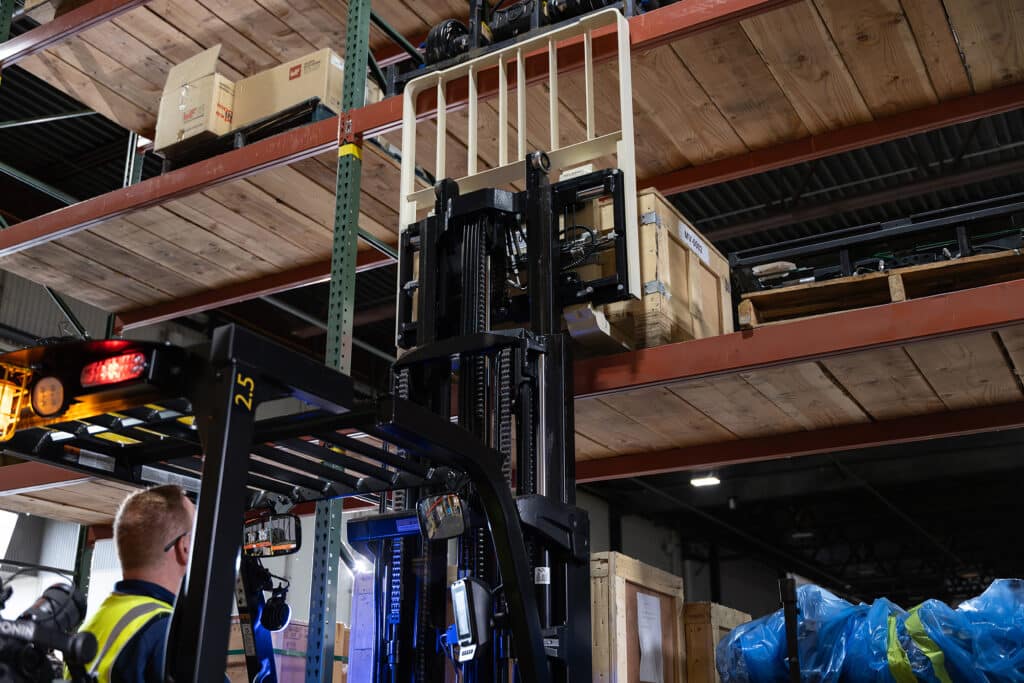 Forklift lifting pallet into place on warehouse shelf