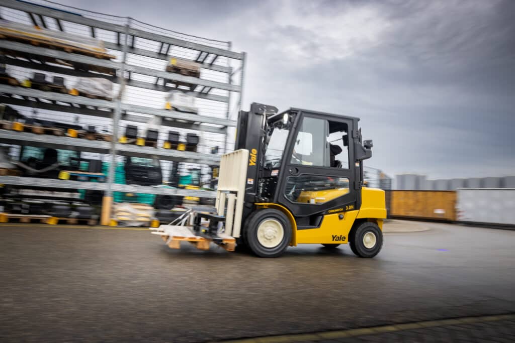 A Yale forklift driving safely with a small load on the forks.