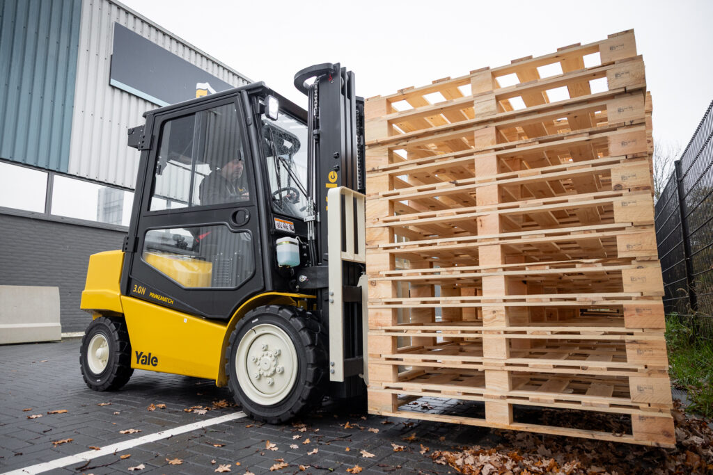 Yellow Yale forklift moving a stack of pallets outdoors